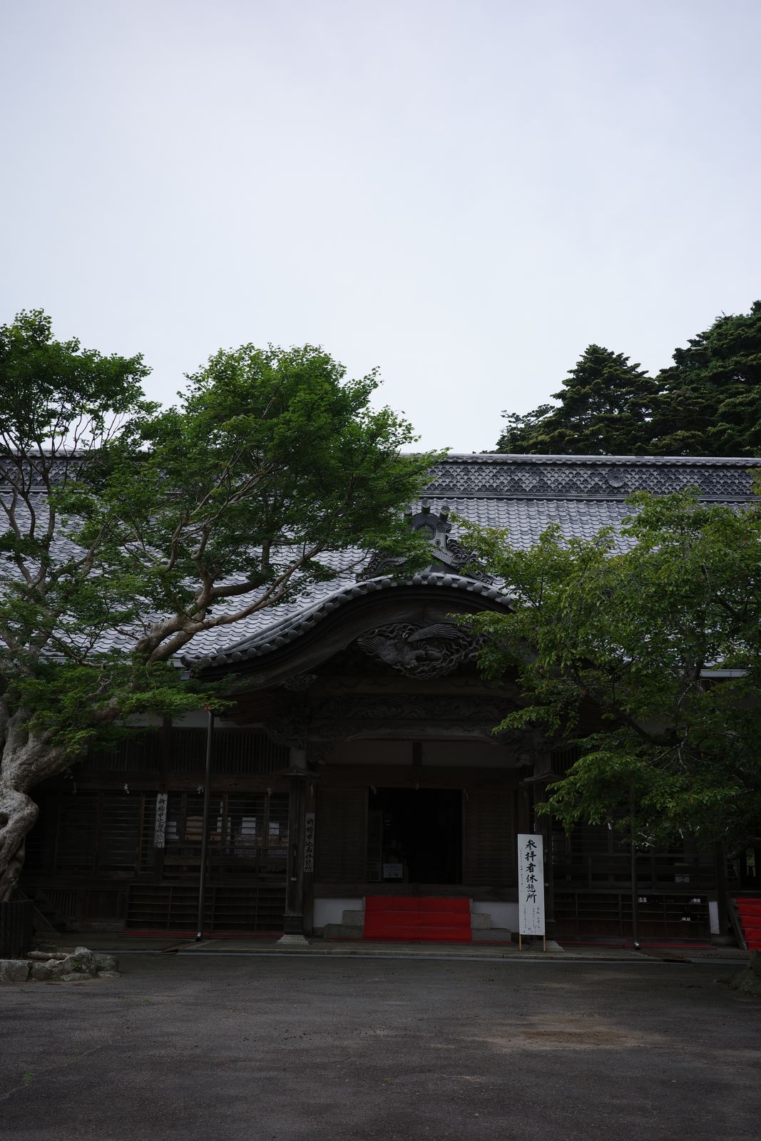 瓦屋根の大きな木造建築。入口に「参拝者休憩所」と書かれた白い看板が立っている